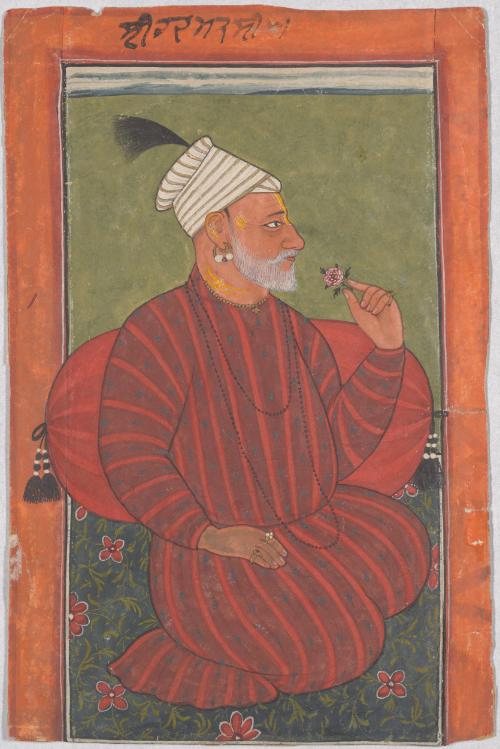Seated man smelling a flower